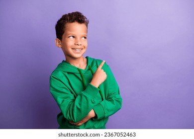 Photo of dreamy thoughtful little boy dressed green hoodie pointing finger looking empty space isolated purple color background - Shutterstock ID 2367052463