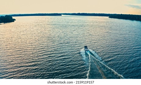Photo from a drone above a river with a fast driving speedboat while sunset. Aerial view of driving powerboat on lake.	