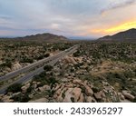 photo from a drone of rocky mountains, large stones stand on top of each other, there is a road between the mountains and the sunset