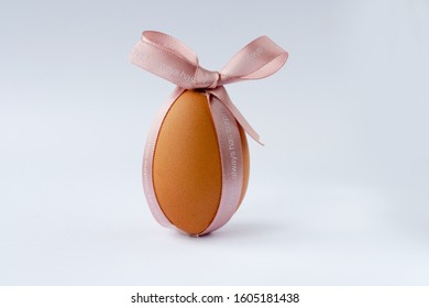 Сreative photo with easter orange egg and pink ribbon on a grey background.  - Shutterstock ID 1605181438