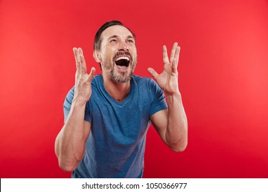 Photo of ecstatic man screaming and rejoicing with gesturing like winner or successful person isolated over red background
