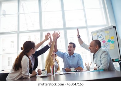 Photo editors giving high-five in meeting room at creative office