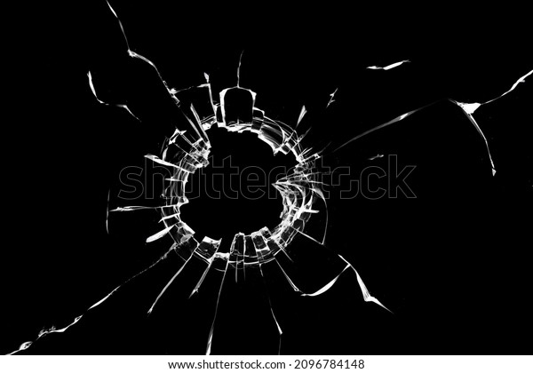 Photo effect of broken glass, a hole with\
cracks in the glass on a dark\
background