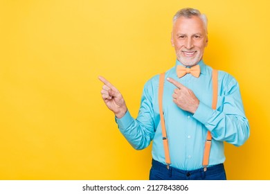 Photo of elder white hairdo man index promo wear teal shirt suspenders bow tie isolated on yellow color background