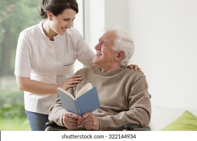 Photo of elderly man reading book and his private nurse - Powered by Shutterstock
