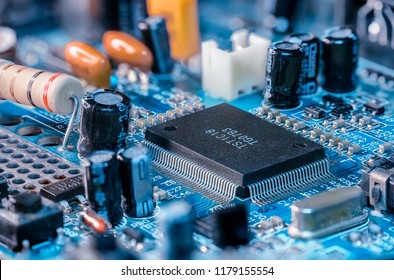 Photo of  electric component in electronic device, contain black microchip as main object, black capacitor and big resistor on blue printed circuit board. Captured using focus stacking method
