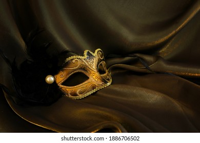 Photo of elegant and delicate gold Venetian mask over dark silk background