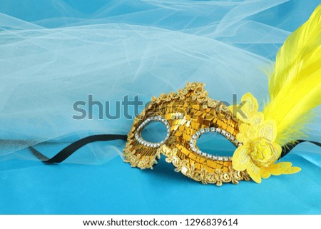 Photo of elegant and delicate gold venetian mask over turquoise silk and chiffon background