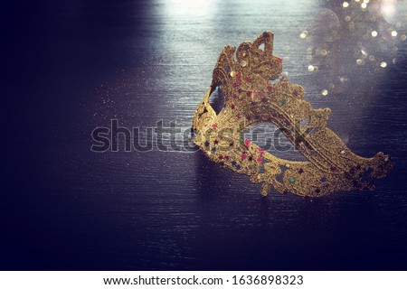 Photo of elegant and delicate gold Venetian mask over dark wooden background