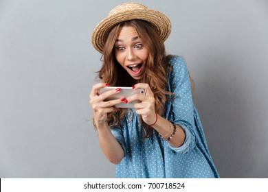 Photo Of Emotional Young Caucasian Woman Play Games By Phone. Looking Aside.