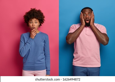 Photo of emotive black woman and man gasp from wonder and shock, hear terrifying news, realize awful accident happened with friend, wear pastel colorful outfits, pose over colored studio wall