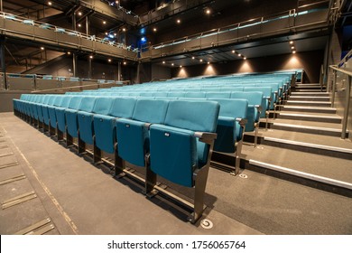 Photo of an empty cinema or theatre showing rows of blue/green foldable seats in the empty building