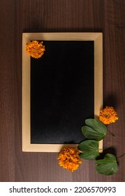 Photo of an empty, clean slate with wooden frame with Apte leaves and marigold flower. Dussehra festival template with blank space for the message. - Shutterstock ID 2206570993