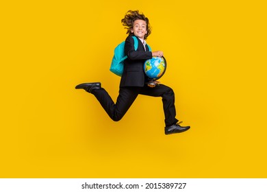 Photo Of Energetic Little Boy Jump Rush Run Hold Globe Wear Rucksack Black Uniform Isolated Yellow Color Background