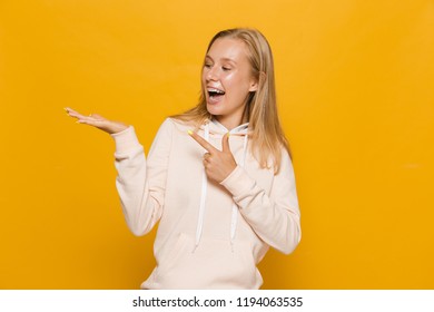 Photo Of European School Girl With Dental Braces Holding Copyspace At Palm Isolated Over Yellow Background
