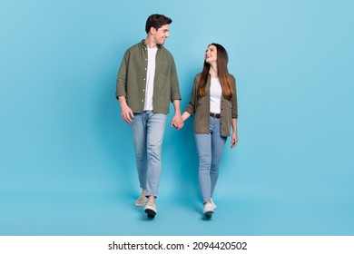 Photo of excited charming young guy woman dressed khaki shirts smiling walking holding arms isolated blue color background - Powered by Shutterstock