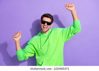 Photo of excited crazy handsome guy open mouth hands up celebrate his weekend chill dancing wear ray ban sunglasses isolated on purple color background