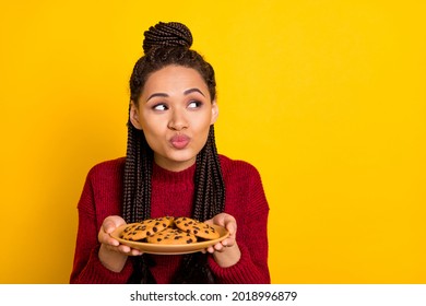 Photo Of Excited Flirty Lady Wear Red Pullover Sending Kiss Holding Cookies Plate Looking Empty Space Isolated Yellow Color Background