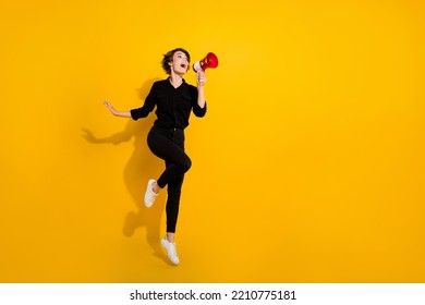 Photo of excited funky lady wear black shirt jumping high shouting announcement empty space isolated yellow color background