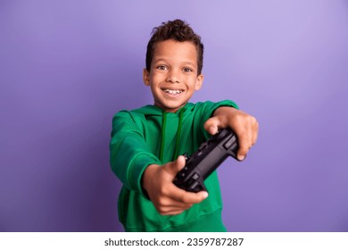 Photo of excited funky small boy wear green sweatshirt enjoying playing playstation isolated violet color background