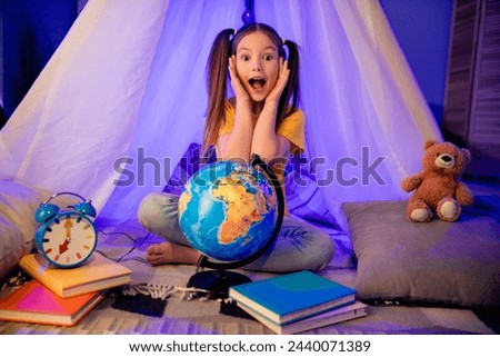 Photo of excited funky small preteen girl wear casual style learning countries sitting hovel indoors room home house