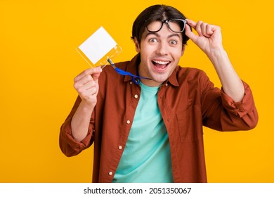 Photo of excited funky young guy dressed brown shirt arm glasses holding name tag smiling isolated yellow color background