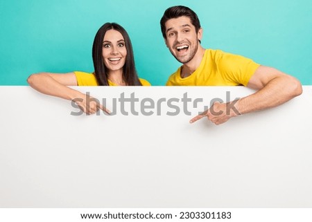 Photo of excited funny husband wife dressed yellow t-shirts showing fingers poster empty space isolated turquoise color background