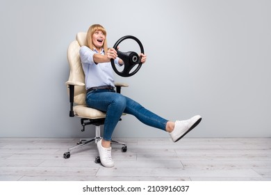 Photo of excited lady dressed white shirt sitting armchair driving car empty space isolated grey color background