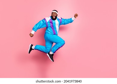 Photo Of Excited Pretty Dark Skin Guy Dressed Sport Suit Headband Smiling Jumping High Running Fast Isolated Pink Color Background