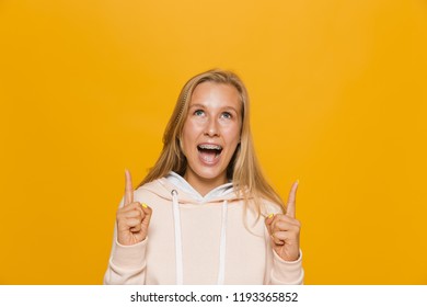 Photo Of Excited School Girl With Dental Braces Pointing Finger Upward At Copyspace Isolated Over Yellow Background