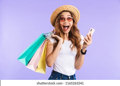 Photo Of Excited Screaming Cute Woman Isolated Over Purple Wall Background Holding Shopping Bags Using Mobile Phone.