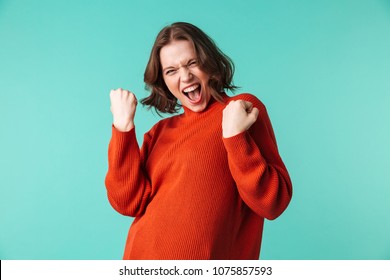 Photo Of Excited Woman Standing Isolated Over Blue Background Looking Camera Make Winner Gesture.