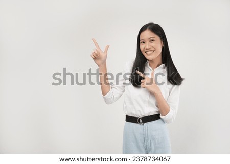 Photo of excited young asian woman, office lady pointing fingers left at discount, showing sale banner, standing over white background