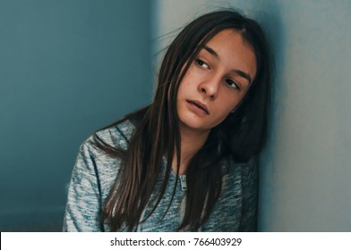 Photo of Expression of lonely female teenager at home. Portrait of a sad teenage girl looking thoughtful about troubles. Pensive teen. Depression, teen depression, pain, suffering.