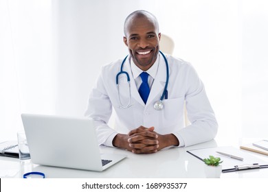 Photo of family doc dark skin cheer guy toothy smile consultant notebook table prescription help patients control panic fear risk epidemic disease wear white lab coat office clinic indoors
