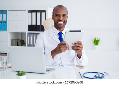 Photo of family doc dark skin professional guy hold digital tablet write online prescription help people control risk epidemic disease workaholic wear white lab coat office clinic indoors - Powered by Shutterstock