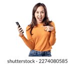 Photo features a happy Indonesian woman wearing an orange sweater and jeans while holding a smartphone, isolated on a white background.