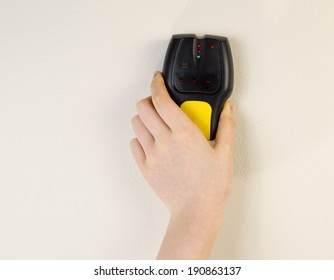 Photo Of Female Hand Holding Stud Finder Against Interior Home White Wall