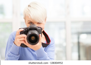 Photo Of Female Photographer With DSLR At Home Sitting On The Floor