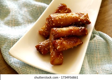 Photo Of Filipino Food Called Turon Or Deep Fried Saba Banana In Spring Roll Wrapper With Brown Sugar And Sesame Seeds.