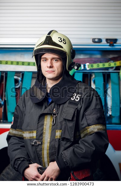 Photo of fireman\
man in helmet at fire\
truck