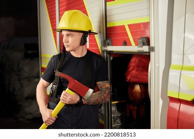 Photo Of Fireman Wearing Helmet With Ax Against Fire Engine. 