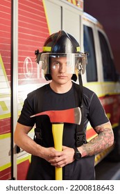 Photo Of Fireman Wearing Helmet With Ax Against Fire Engine. 