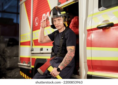 Photo Of Fireman Wearing Helmet With Ax Against Fire Engine. 