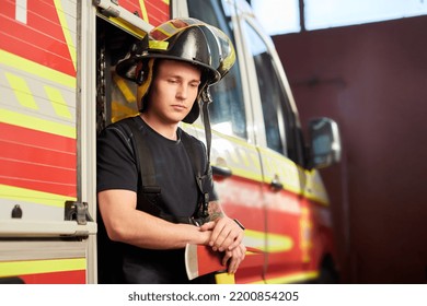 Photo Of Fireman Wearing Helmet With Ax Against Fire Engine. 