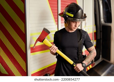 Photo Of Fireman Wearing Helmet With Ax Against Fire Engine. 