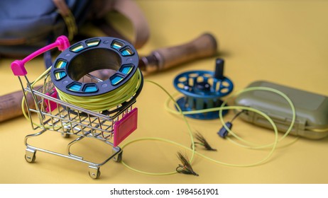 Photo Fishing Rod, Fly Box, Fly Fishing Reel With Line In Mini Cart. Fly Fishing Shopping Concept.