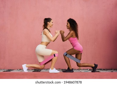 Photo fitness girls in a stylish sports suit squats with rubber bands on the background of a pink wall. Sports woman squats, sits. Copy ad space.
 - Powered by Shutterstock