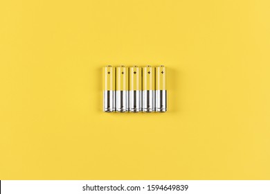 Photo of five gray-yellow alkaline AA batteries on a yellow background. Recycling of rechargeable NiMH batteries. The most popular size of accumulators. Copy space.