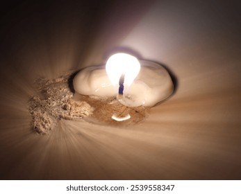 Photo of the flame of a small candle that has begun to dim because it has been burned on a tombstone on the occasion of World Spirits Day - Powered by Shutterstock